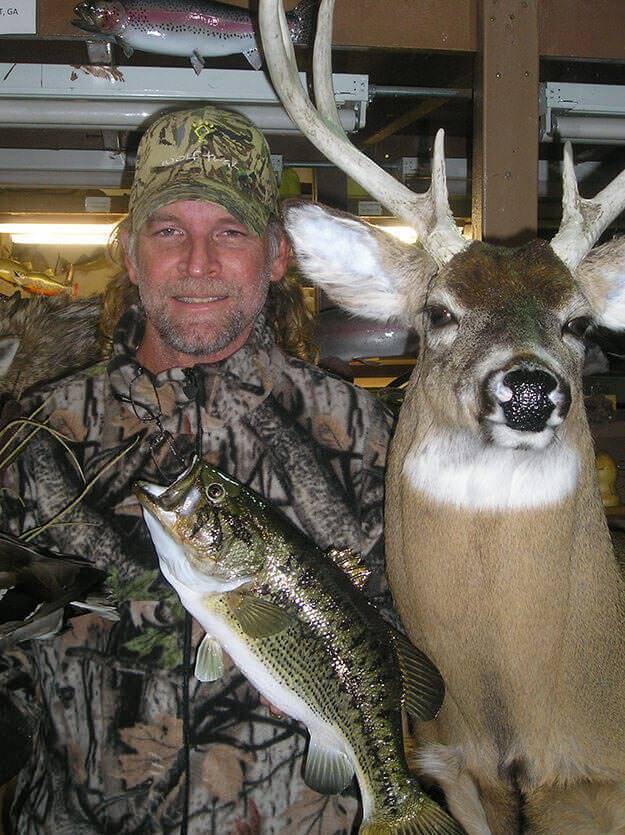 Image of man showing off fish and deer mounts